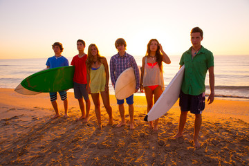 Surfers boys and girls group walking on beach