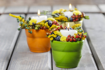 Candle holder decorated with autumn flowers and other plants