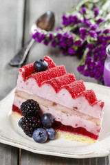 Pink layer cake decorated with fresh fruits on wooden table