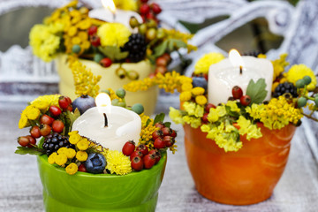 Candle holder decorated with autumn flowers and other plants