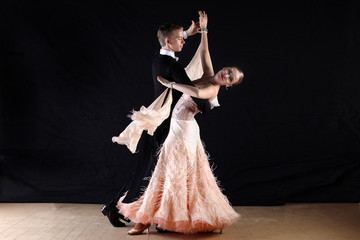 dancers in ballroom against black background
