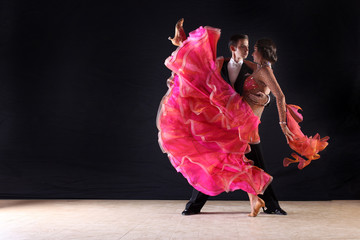 Latino dancers in ballroom against black background