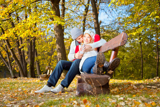 Young romantic couple on a bench in park.