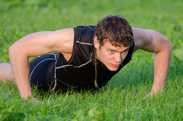 Handsome man doing push-ups at the park