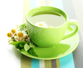 Cup of herbal tea with wild camomiles and mint, isolated