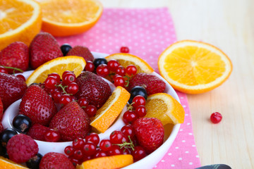 Useful fruit salad in plate on wooden table close-up