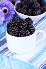 Sweet blackberries in cup on table close-up