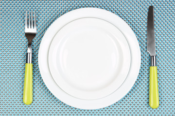 Knife, color plate and fork, on color background