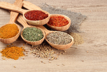 Assortment of spices in wooden spoons on wooden background