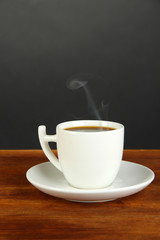 Cup of coffee on wooden table on black background