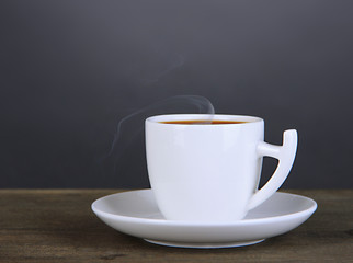 Cup of coffee on wooden table on black background