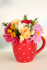 Beautiful bouquet of bright flowers in color mug,