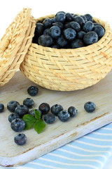 Blueberries in wooden basket on board on napkin