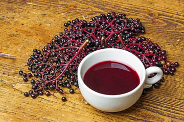 a cup with elder juice on a wooden table