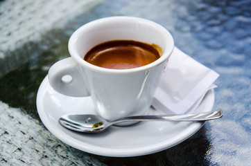 White espresso cup standing on the glass table of street cafe