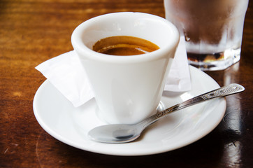 White espresso cup with glass of cold water on the wooden table