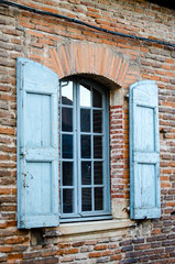 Fototapeta na wymiar Traditional french window with blue shutters on the brick facade