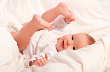 Obraz na płótnie Canvas Happy baby plays with his legs