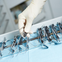 Hand of dentist reaching for dental instruments