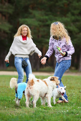 Two women with a group of dogs in the park