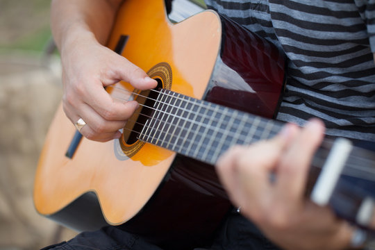Man playing acoustic guitar close up outdoors