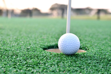 Golf ball sits at the lip of the hole on the putting green