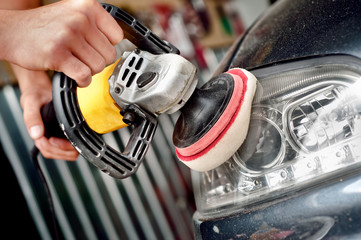 Car headlight cleaning with power buffer machine at car service