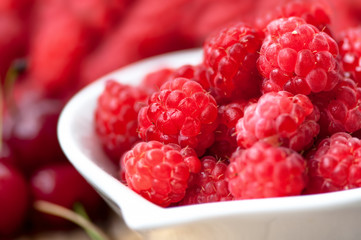 Organic and healthy raspberry in white bowl with wild berries on