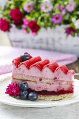 Pink layer cake decorated with fresh fruits on wooden table