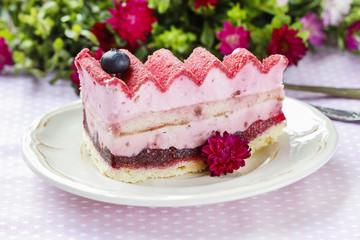 Pink layer cake decorated with fresh fruits on wooden table