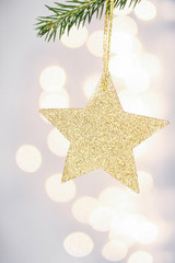Fototapeta na wymiar Christmas card with golden star and pine branch on Defocused Chr