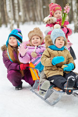 Older girl pushes sled with two little children