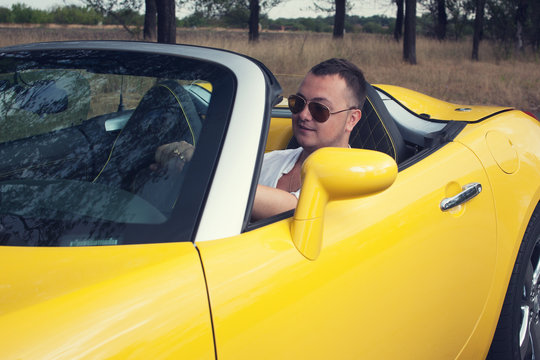Trendy young man driving two seat cabrio car