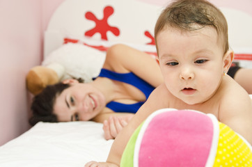Mother and baby relaxing on bed.