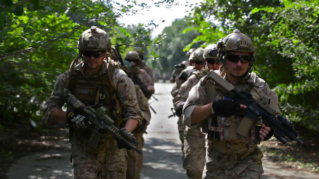 Medium shot of soldiers running in formation with weapons. Suitable for military training, tactical exercises and combat preparation visuals