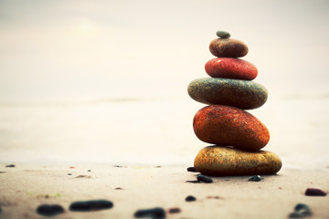 Stones pyramid on sand symbolizing zen, harmony, balance