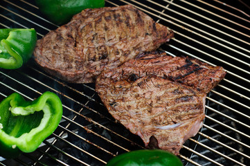 Steaks with green peppers on a grill