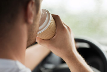 man drinking coffee while driving the car