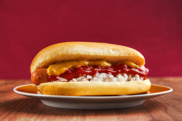 Hot dog on wooden table, red background