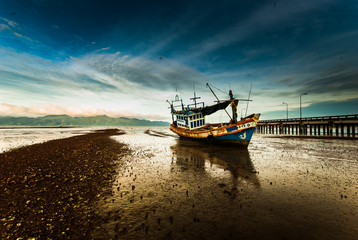 Fishing boat ran aground on the mud beach with the morning ligth
