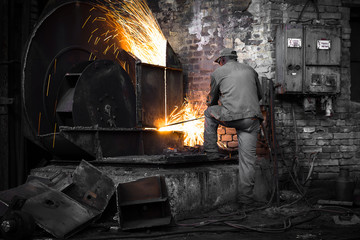 worker in factory cutting steel pipe using metal torch