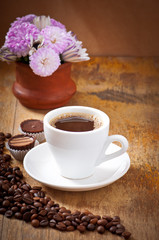 cup of coffee and chocolate candy on a old wooden table