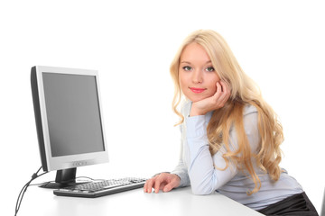 Young cute girl behind a desk with a computer and a monitor