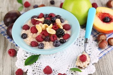 Oatmeal in plate with berries on napkins on wooden table