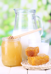 Honey and milk on wooden table on natural background