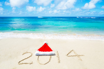 Number 2014 with christmas hat on the sandy beach