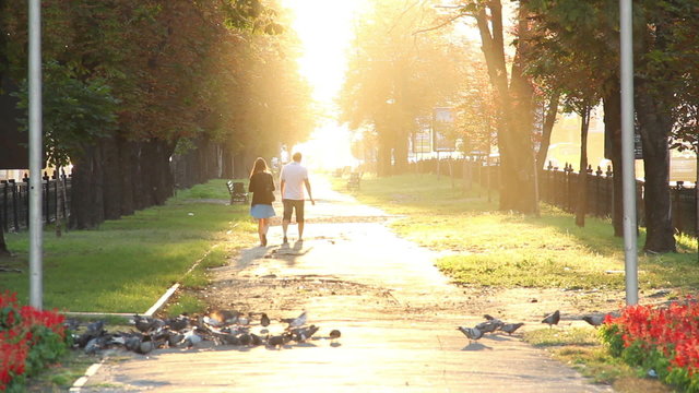 Man and woman in park walking away to heaven, sun