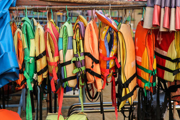 Old colorful life jackets for rent. - obrazy, fototapety, plakaty