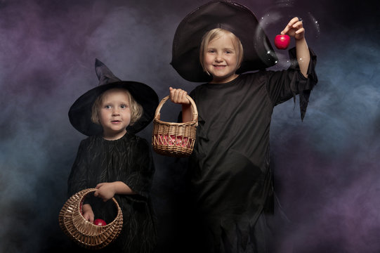 two little halloween witches, colorful smoke in the background