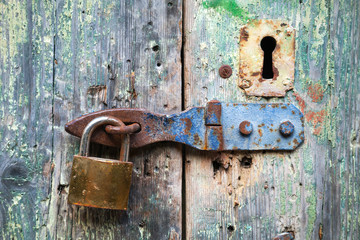 Old lock and rusted keyhole on green wooden door